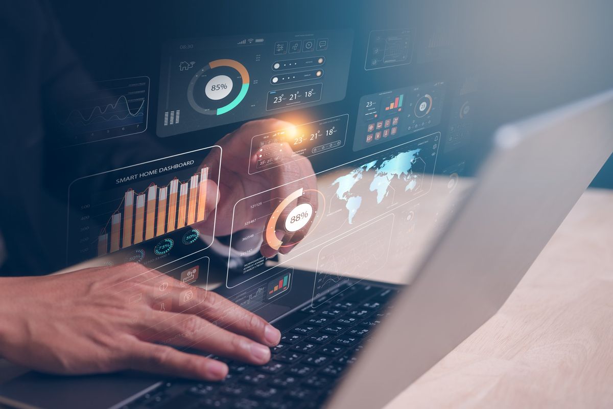 Person at a laptop with marketing analytics dashboards, percentage gauges and bar charts displayed above the keyboard
